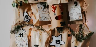 Papierowy kalendarz adwentowy z ponumerowanymi torebkami i gałązkami świerku.